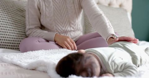 Mother Comforting Infant on Bed in Cozy Bedroom