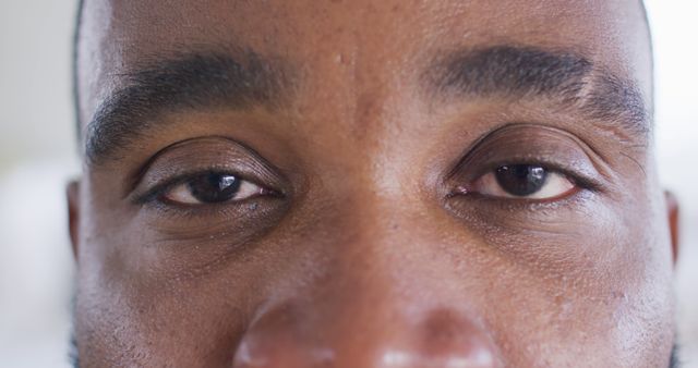 Close-up view of an African American man's eyes. Suggests calmness and deep thought. Ideal for use in advertisements focusing on emotions, mental health initiatives, graphic design portraits, or content on focus and concentration.