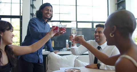 Young professionals toasting drinks in modern kitchen during casual after-work celebration