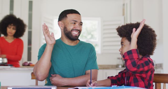 Father High-Fiving Young Son While Doing Homework at Kitchen Table - Download Free Stock Images Pikwizard.com