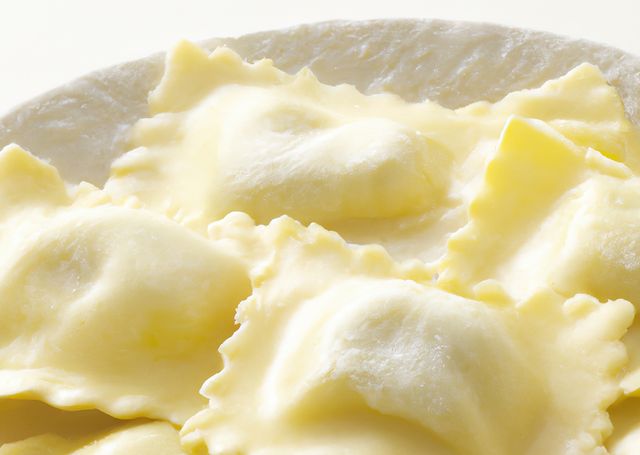 Close up of multiple ravioli and flour on white background created using generative ai technology. Cooking and food concept, digitally generated image.