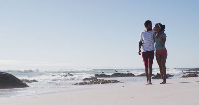 African american couple smiling, embracing and walking on the beach. healthy outdoor leisure time by the sea.