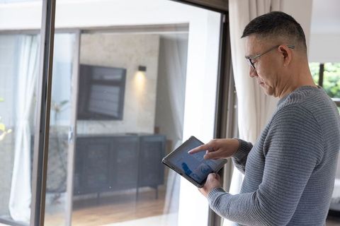 Senior man using tablet for home automation inside modern living room