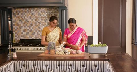 Mother and Daughter in Traditional Saris Unpacking Groceries in Kitchen