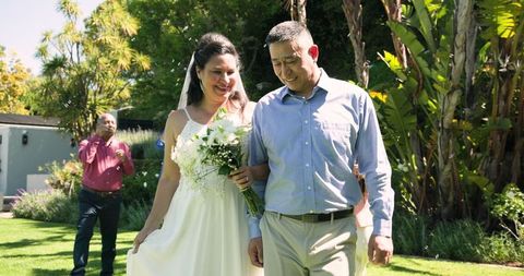 Bride and groom walking in sunny garden on wedding day