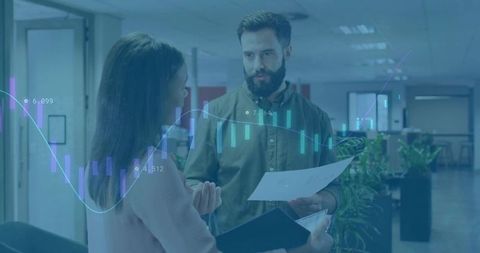 Colleagues discussing financial data in office corridor