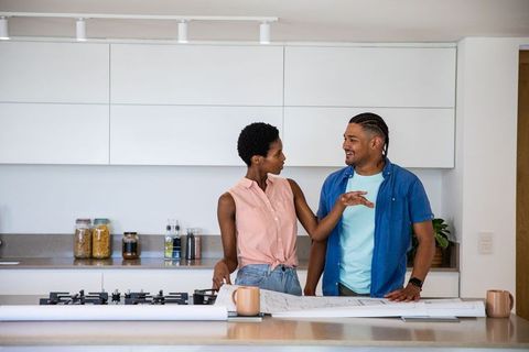 Multicultural Couple Discussing Home Blueprints in Modern Kitchen