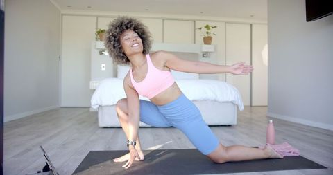 Smiling Woman Practicing Yoga and Stretching in Bedroom
