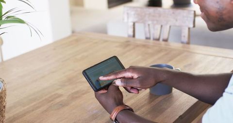 Man Using Smartphone App for Energy Management While Enjoying Coffee
