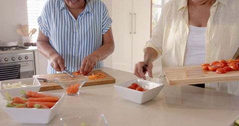 Senior Female Friends Cooking Together in Modern Kitchen