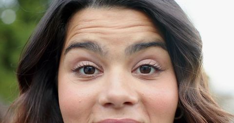 Close-up young woman smiling outdoors showing natural makeup and gold hoop earring