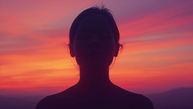 Female Silhouette Against Vibrant Sunset Sky in Scenic Landscape