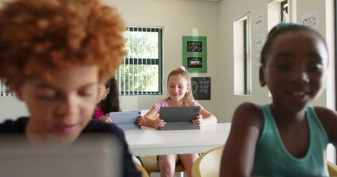 Elementary students using tablets in modern classroom for collaborative digital learning