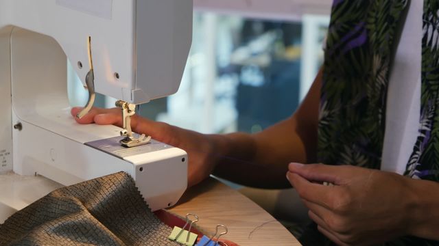 This video depicts a young biracial male fashion designer in a modern office environment focused on using a sewing machine. Ideal for content related to the fashion industry, sewing tutorials, crafts, tailoring courses, and fashion designer profiles.