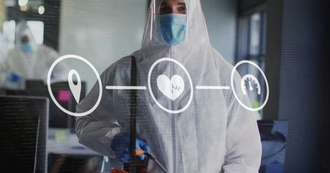 Sanitation worker wearing full ppe spraying office workspace with disinfectant wand