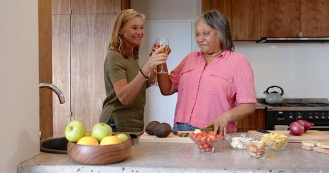 Female Friends Toasting in Rustic Kitchen During Meal Preparation