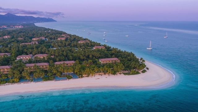 Sunrise crescent beach resort with palm-lined villas, turquoise water, private pools and sailboats