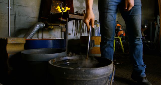 Blacksmith Dipping Hot Metal Into Water Cooling Bucket in Workshop - Download Free Stock Images Pikwizard.com