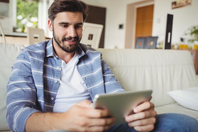 Man using digital tablet while relaxing on sofa in the living room