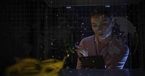Female it specialist analyzing data in dark server room