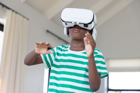 African american boy exploring virtual reality with white vr headset in modern living room