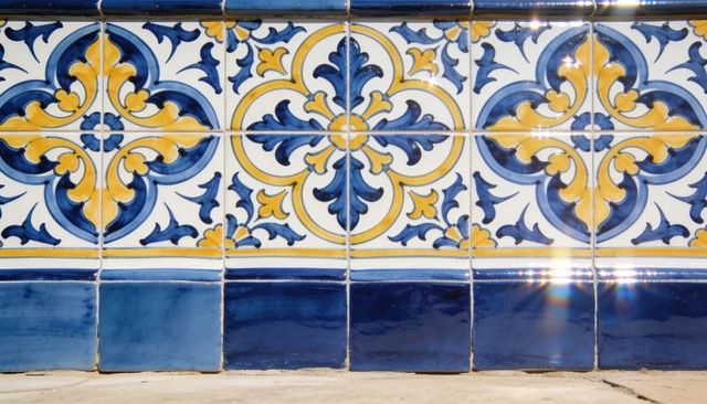 Cobalt and yellow arabesque ceramic tile frieze on exterior stair riser with sun glare