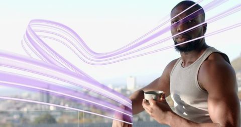 Athletic man sipping coffee on balcony with urban skyline and flowing purple light trails