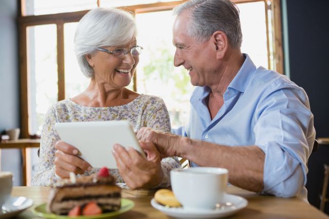 Happy senior couple using digital tablet in cafÃ©