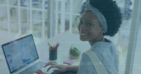Woman Analyzing Financial Data on a Laptop in Bright Modern Office