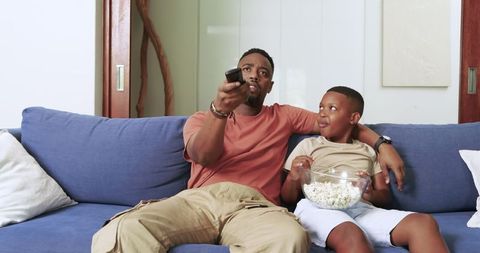 Father and Son Relaxing on Sofa Watching TV Together