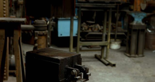 Dusty, rustic workshop shows metalworking tools and equipment including a vice and anvil. Used for illustrating industrial or artisanal themes, showcasing craftsmanship, manufacturing processes, or vintage work environments. Ideal for backgrounds, headers, or content about trades and craftsmanship.