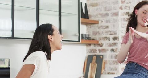 Multiracial friends celebrating engagement in sunlit kitchen
