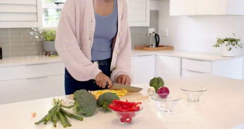Woman slicing yellow bell pepper in modern kitchen