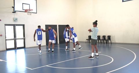 Basketball team huddling and strategizing near hoop on court