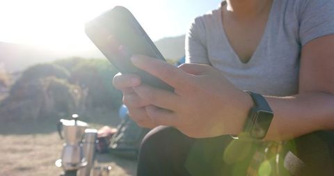 Woman Using Smartphone Outdoors During Camping Adventure