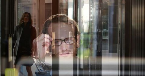 Urban double exposure businessman adjusting glasses in glass lobby with traveling woman