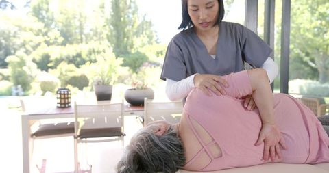 Physiotherapist Assisting Senior Woman with Stretching Exercise