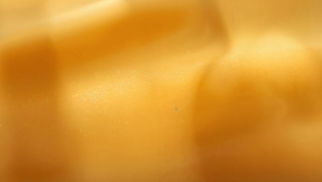 Macro abstract golden texture showing smooth speckled surface and shallow ridges glossy