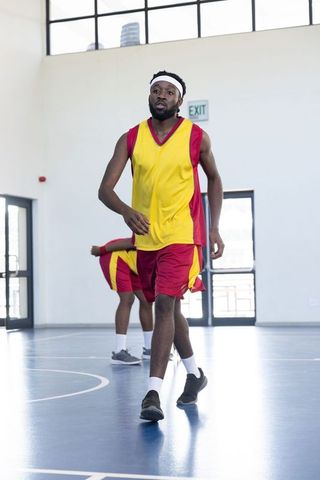 Athletes in Bright Uniforms Preparing for Basketball Game Indoors
