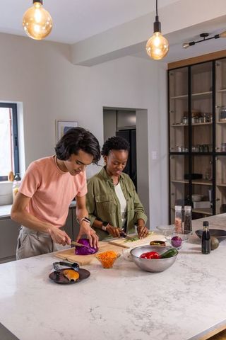 Couple chopping colorful vegetables on marble kitchen island in modern daylight
