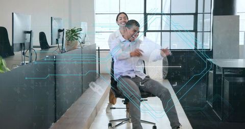 Coworkers pushing rolling chair laughing with futuristic hud overlay in open office