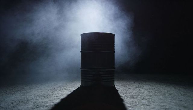Barrel silhouetting in fog with rimlight casting long shadow, moody industrial minimal