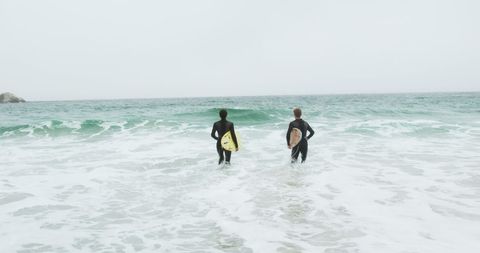 Surfers running towards ocean with surfboards
