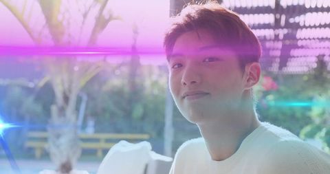 Serene young man in white sweater on sunlit patio