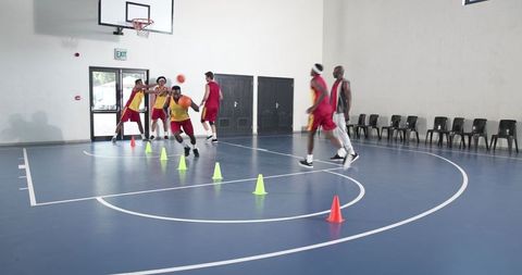 Male Basketball Team Practicing Dribbling in Indoor Gym