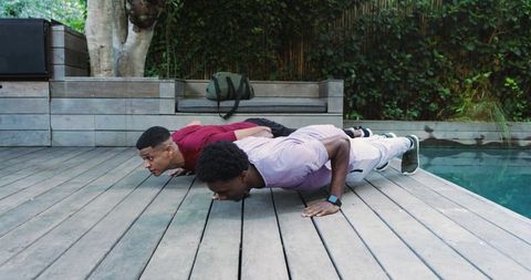 Active friends exercising outdoors by pool on sunny day