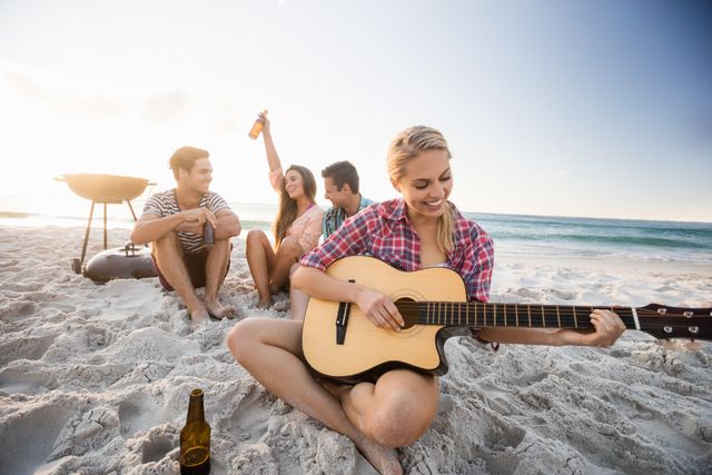 Group of friends relaxing on the beach during sunset, playing guitar and enjoying a bonfire. Perfect for themes related to summer vacations, outdoor activities, friendship, and leisure. Ideal for travel blogs, lifestyle magazines, and promotional materials for beach resorts or summer events.