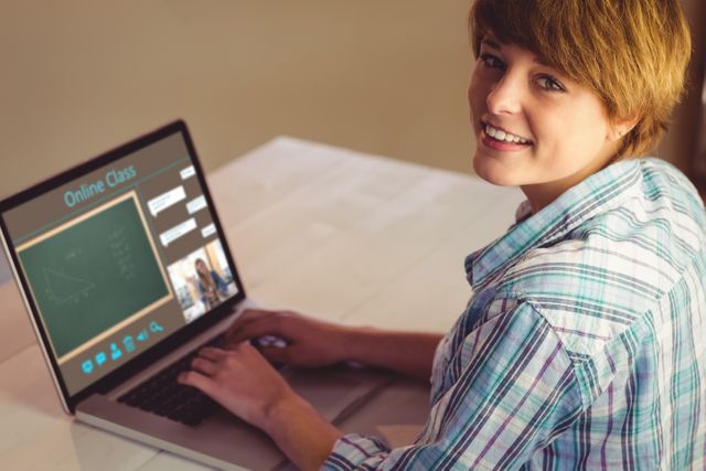 Young adult attending an online class on a laptop while smiling. Suitable for use in articles about virtual learning, remote education, technology in education, or e-learning platforms. Perfect for educational blogs, e-learning websites, or technology-focused publications.