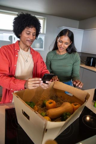 Couple unpacking fresh produce box in modern kitchen