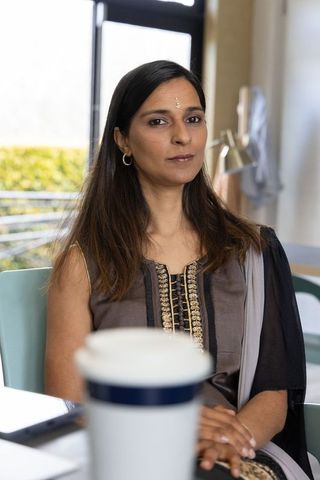 Indian businesswoman sitting at desk wearing embroidered gold kurta and sheer dupatta